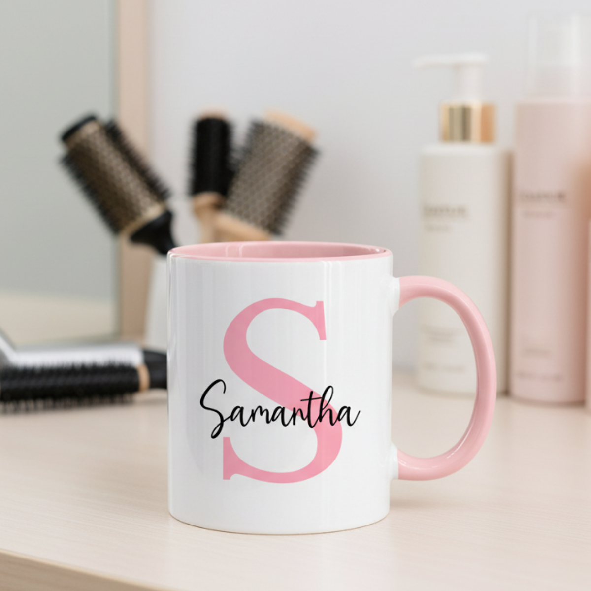 A pink ceramic mug with a white letter 'S' and the name 'Samantha' printed in black.