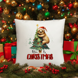Decorative pillow with a sloth and Christmas tree design in front of a Christmas tree and presents.