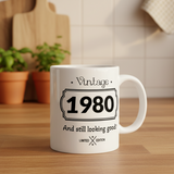 White mug with 'Vintage 1980 And still looking good!' text on a wooden surface.