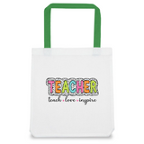 A white tote bag with green handles featuring a colorful text design that reads 'TEACHER' with a decorative pattern and the words 'teach', 'love', 'inspire' in a smaller font.